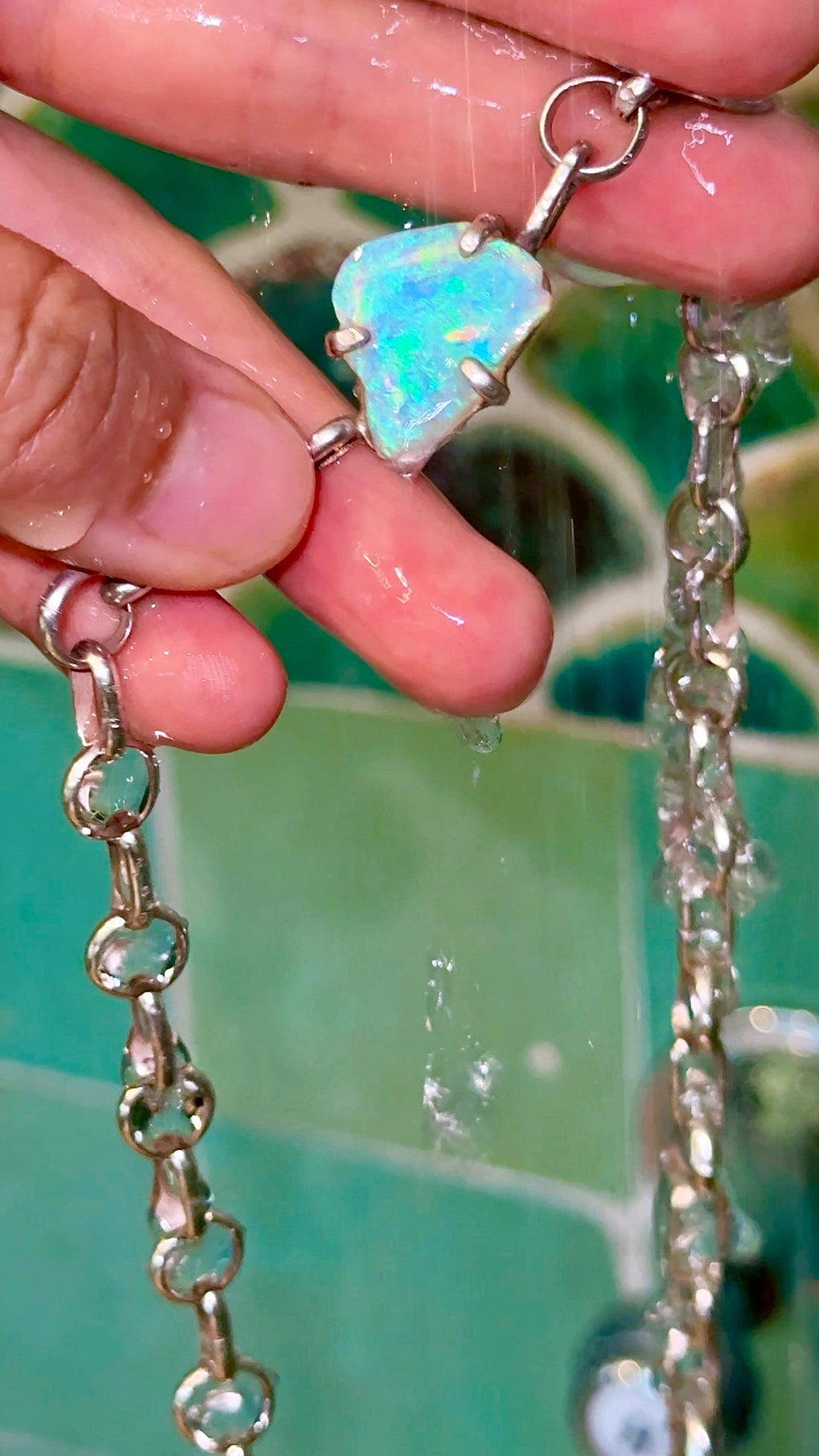 Handcrafted Organic Shaped Ice Blue opal chunky chain necklace held in water to demonstrate water resistance.
