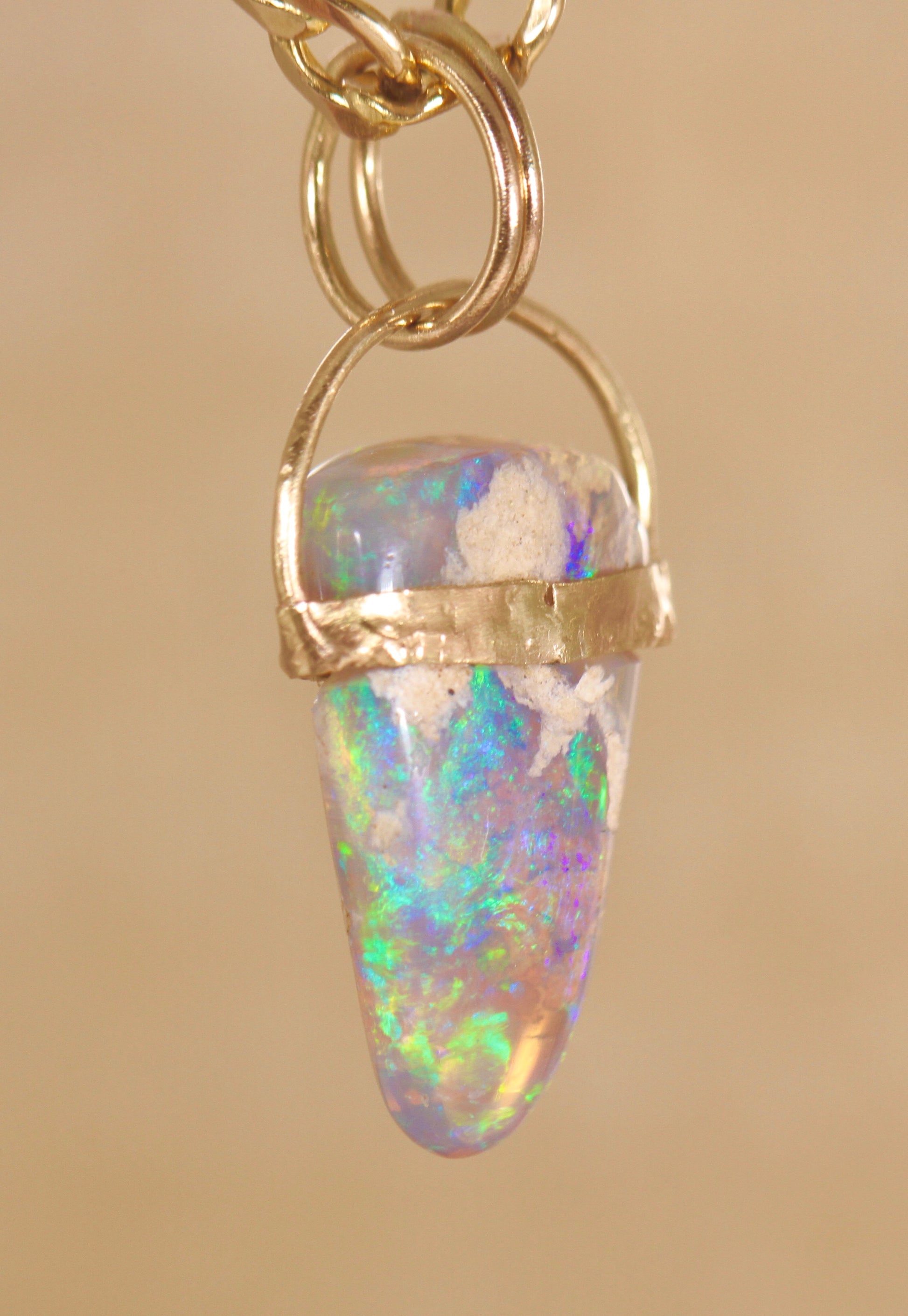 Opal pendant with gold setting on a beige background