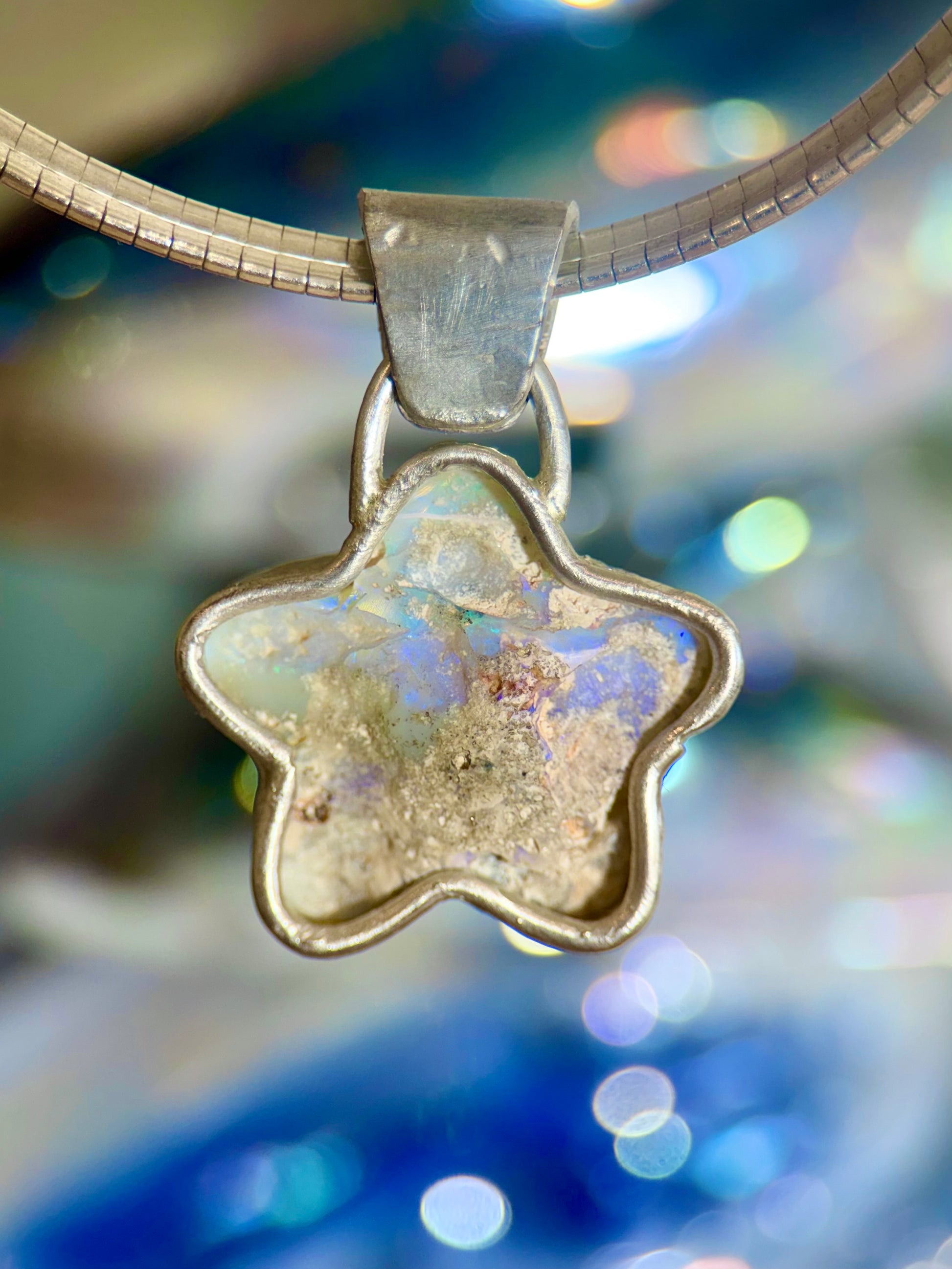 Star-shaped opal pendant with a textured surface on a blurred background
