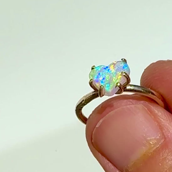 Holding the Rainbow Heart natural Australian crystal opal solid gold ring in the sunlight. 